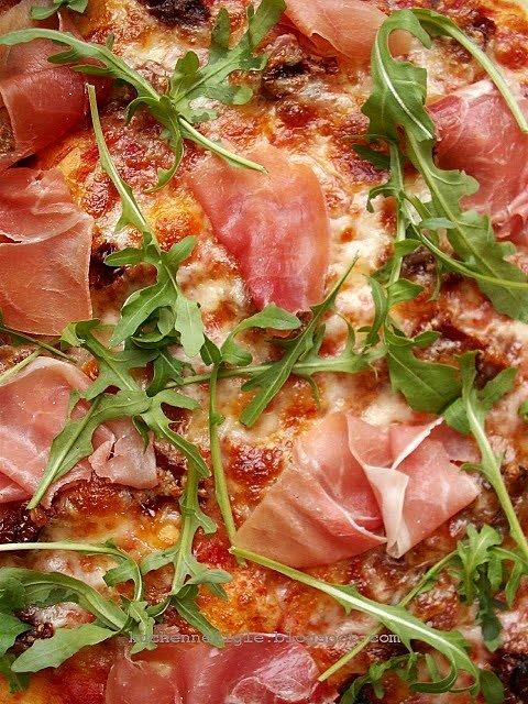 Pizza na cienkim cieście z szynką parmeńską rukolą i suszonymi pomidorami