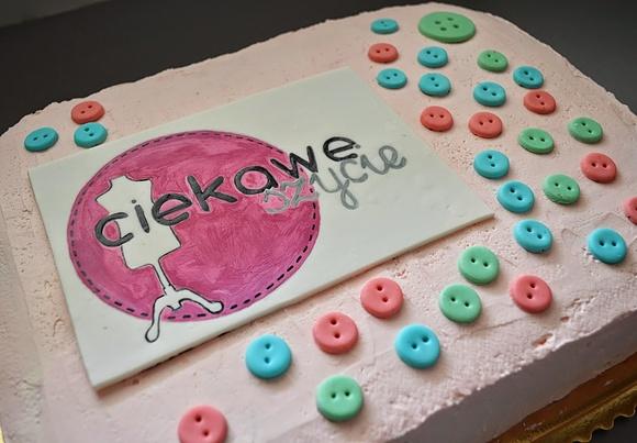 Tort z logo z bitą śmietaną i truskawkami