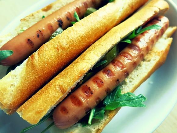 Hot dog z grilla z kiszonym ogórkiem, rukolą i sosem