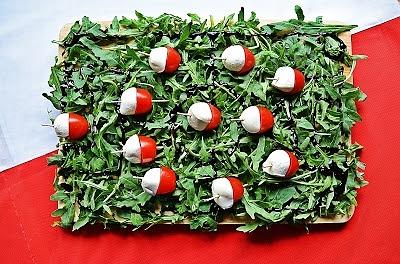 Biało-czerwone przekąski z mozzarellą i pomidorkami na rukoli