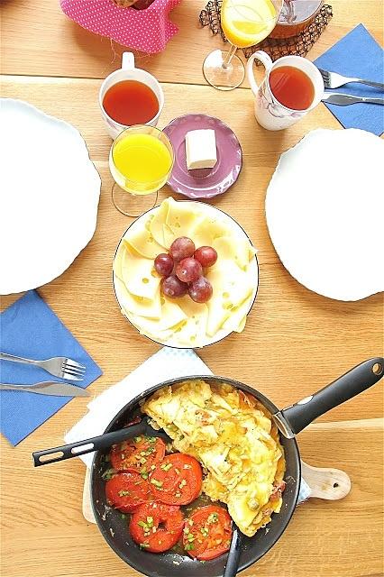 Omlet z szynką dojrzewającą i smażone pomidory na śniadanie przy stole