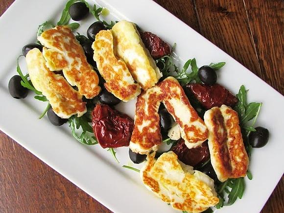 Grillowany ser halloumi na rukoli z suszonymi pomidorami i oliwkami