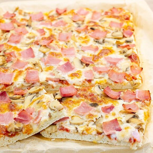 Pizza z blachy z serem mozzarella, szynką i pieczarkami